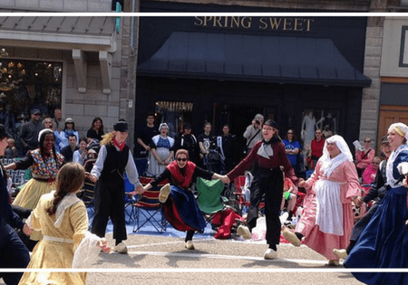 Performers in colonial costumes dancing outdoors