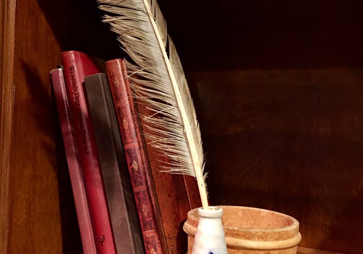 Quill pen in ceramic holder with red books