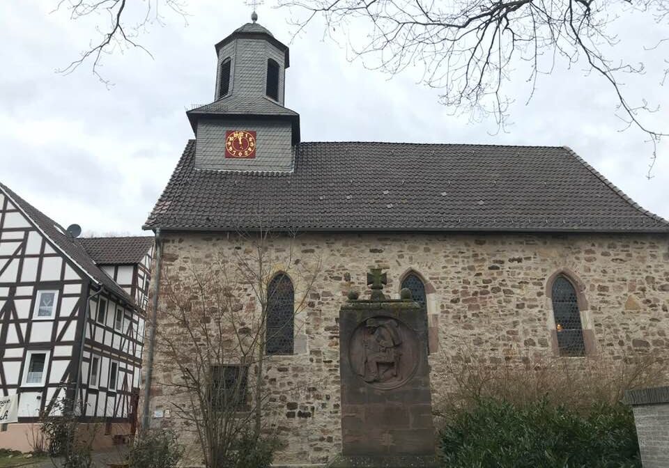 Stone village church with clock tower and monument