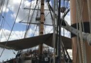 View along the deck and rigging of a historic sailing ship on a cloudy day.