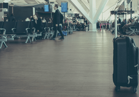 People walking and sitting in a spacious airport terminal.