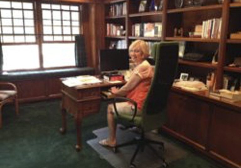 Smiling woman at desk in cozy wood-paneled office
