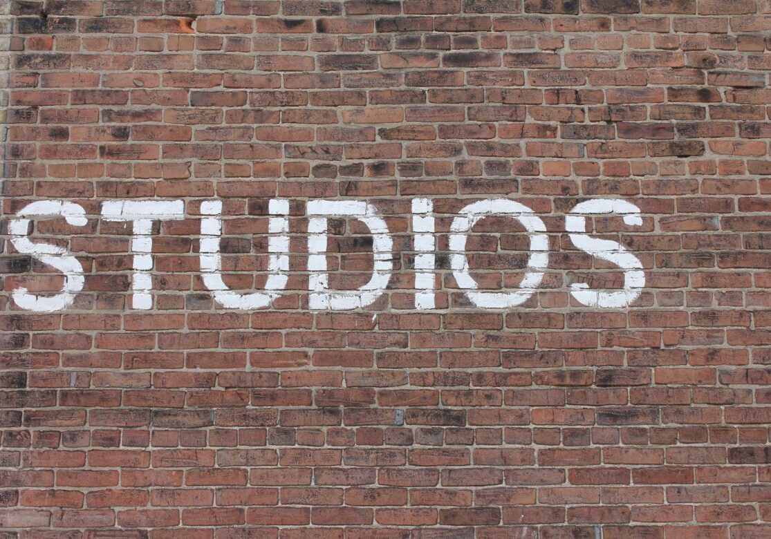 White text 'STUDIOS' painted on a brick wall.
