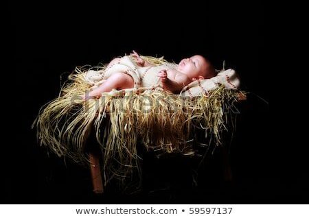 Newborn sleeping on straw in wooden manger