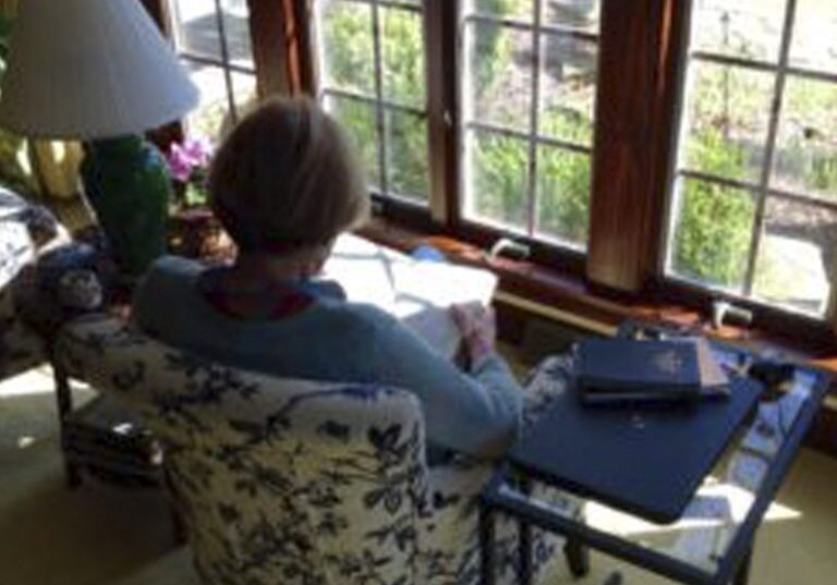 Person reading at a sunlit desk by window