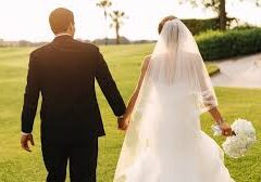 Newlywed couple holding hands walking outdoors at sunset.