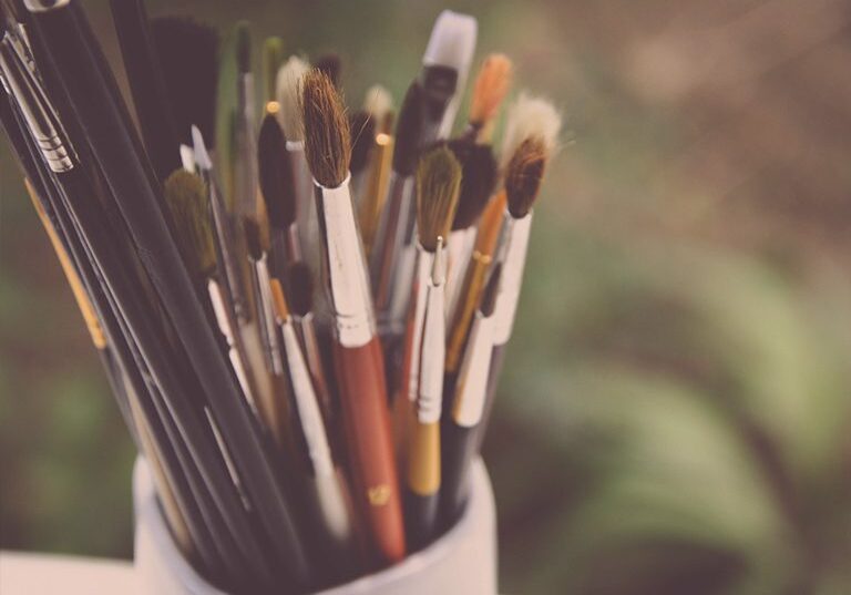 Assorted artist paintbrushes in a white jar